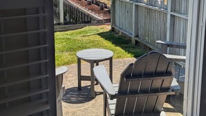 Een terras met een tafel en stoelen, een houten hek en uitzicht op een waterpartij en heuvels.
