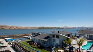 Een modern huis met een zwembad, een steiger met boten en uitzicht op het water en de heuvels.