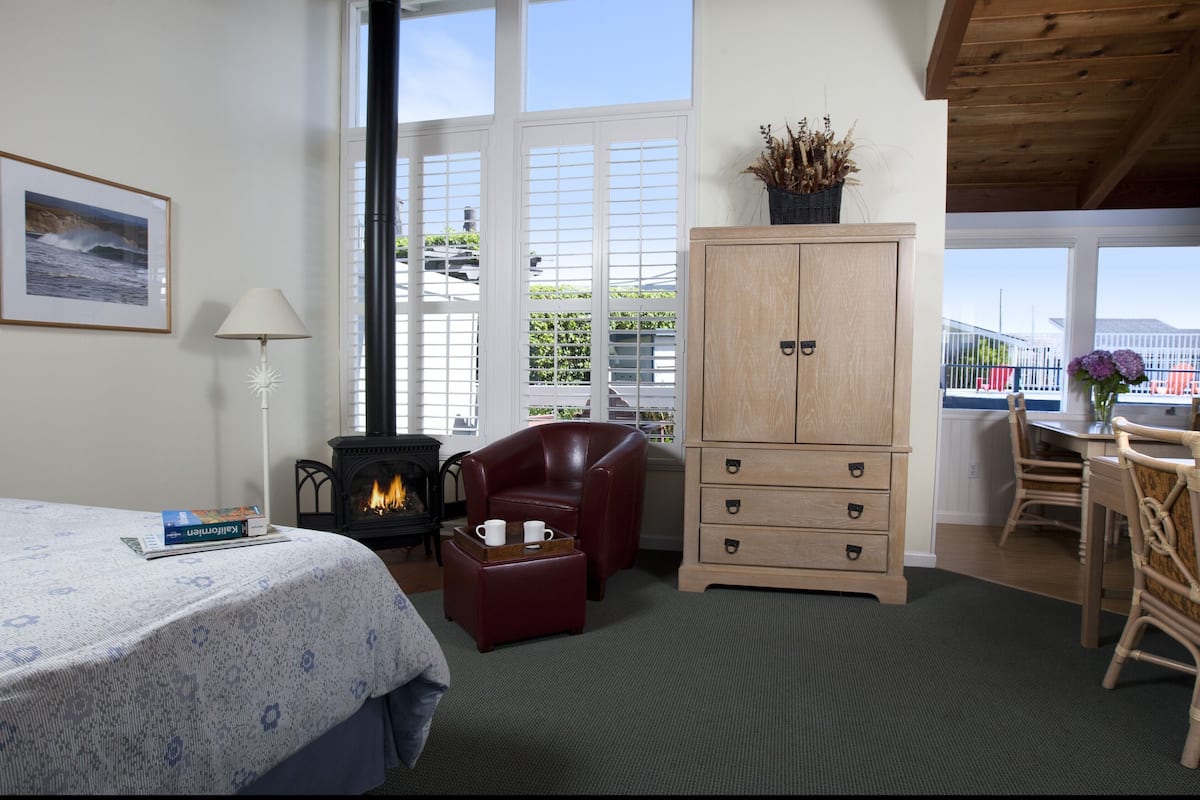 Une pièce chaleureuse comprenant un lit, une cheminée, un meuble en bois et un coin repas avec des chaises.