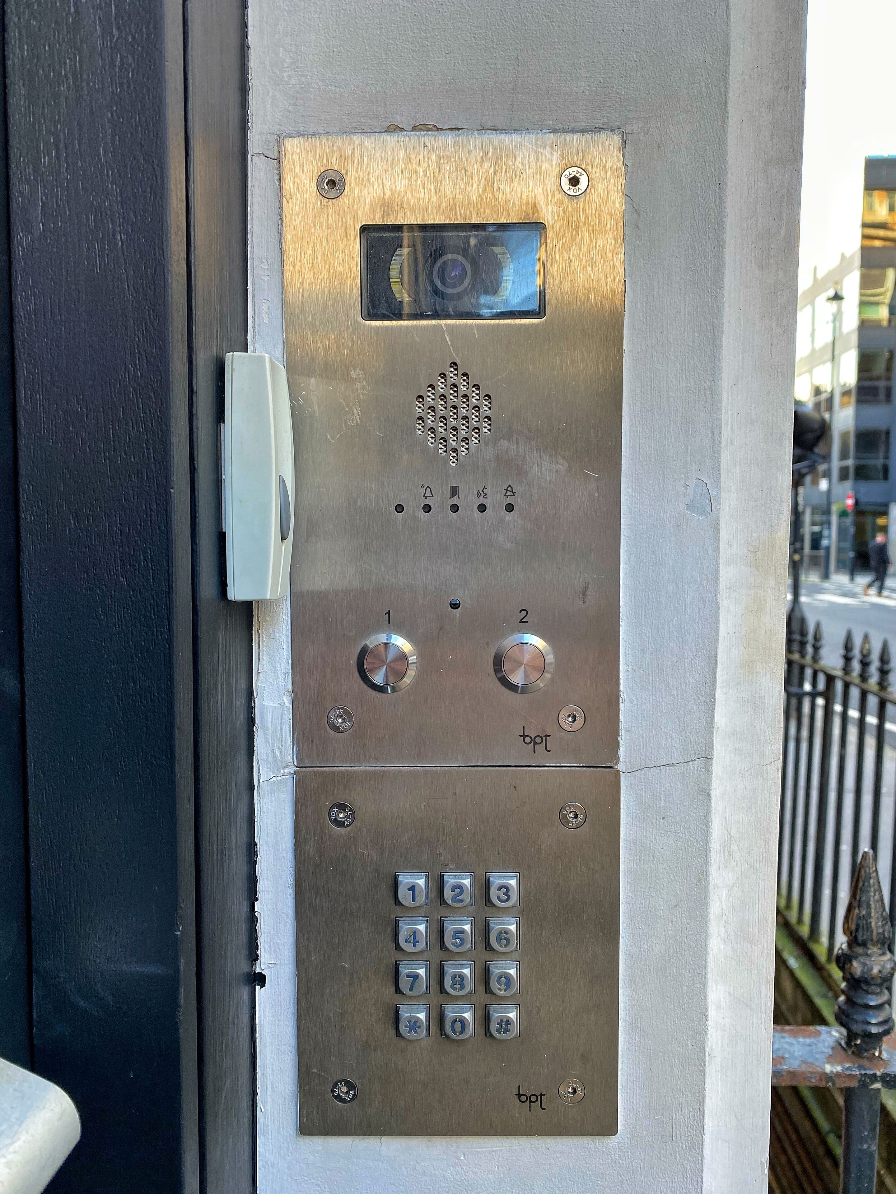 A metallic elevator control panel with a keypad and two buttons above it.