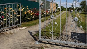 Une entrée fermée par un portail, avec un chemin pavé menant à un bâtiment.