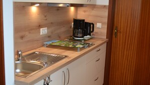 Une cuisine de taille réduite, dotée d’un plan de travail en bois, d’un évier en acier inoxydable et d’une machine à café.