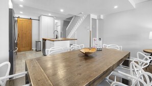 A modern kitchen with white cabinetry, a wooden island, and a stainless steel refrigerator. - Luxury Condominium with Rustic Minimalist Style (Mont-Tremblant)