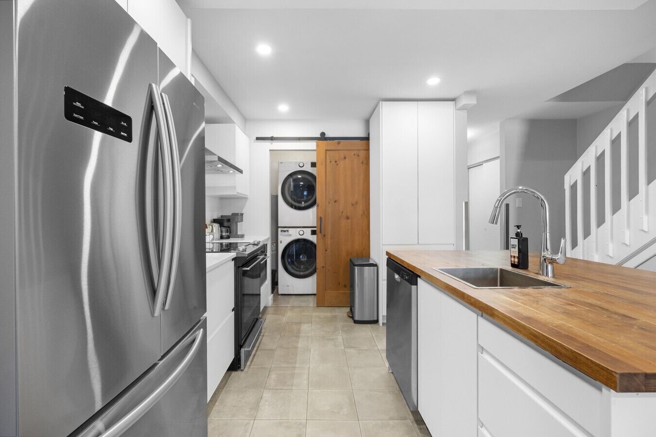 Een moderne keuken met roestvrijstalen apparatuur, een houten aanrechtblad en een ingebouwde wasmachine.