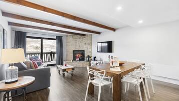 Una sala moderna con chimenea, un comedor con mesa de madera y sillas blancas, y una pared de acento de piedra.