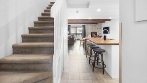 A staircase leading to a living area with a fireplace, bar stools, and a view of the outdoors. - Luxury Condominium with Rustic Minimalist Style (Mont-Tremblant)