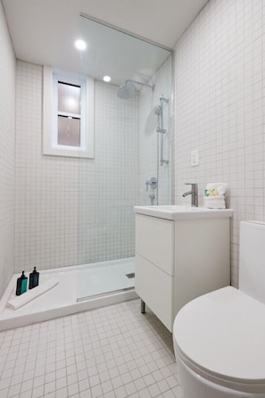 A modern bathroom with a shower, toilet, and sink.