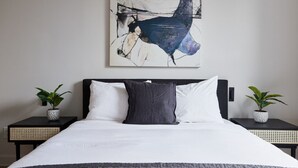 A modern bedroom with a large bed, two bedside tables with potted plants, and a large abstract painting on the wall. - New and Cozy 3 bedroom in Le Plateau by Denstays (Montreal)