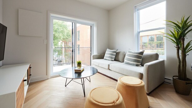 A modern living room with a sofa, two ottomans, a coffee table, and a TV. - New and Cozy 3 bedroom in Le Plateau by Denstays (Montreal)