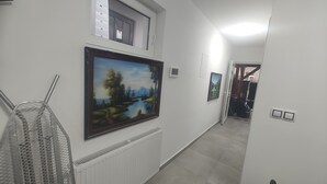 A hallway with two framed landscape paintings, a radiator, and a door leading to another room. - Vu's Home - Apartment Junior - 40m2 (Hlavní město Praha)