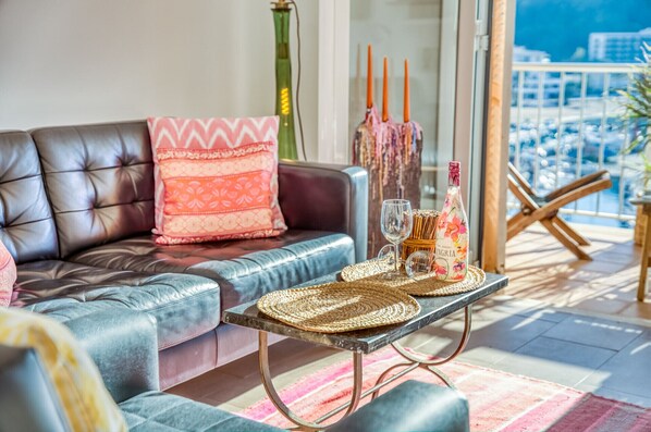 Een moderne woonkamer met een leren bank, een bijzettafeltje met geweven onderzetters en een fles wijn.