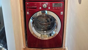 Eine rote, frontbeladene LG Waschmaschine mit Bedienfeld und einer kleineren Waschmaschine darunter.