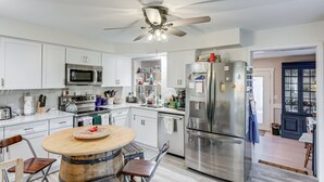 Una cocina moderna con armarios blancos, electrodomésticos de acero inoxidable y una mesa de comedor de madera.