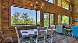 A wooden interior with a dining table, chairs, and a sofa. - Mtn Views, Fireplace, & 2-Story Wall of Windows!🔥 (Sevierville)