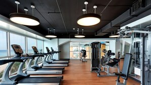 A gym with treadmills, weight machines, and a view of the ocean.