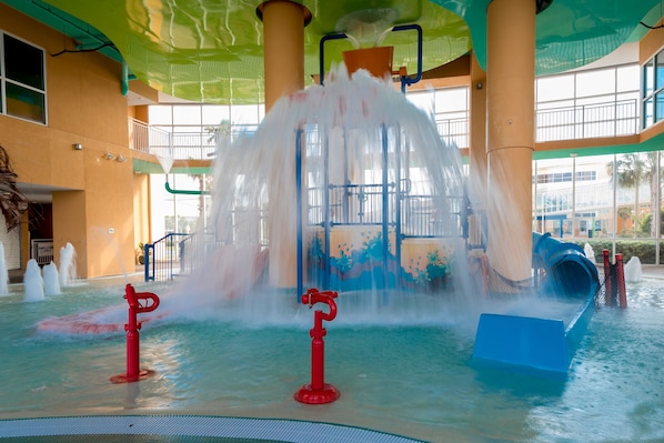 Un espace de jeux aquatiques doté de plusieurs jets d’eau et d’un toboggan.