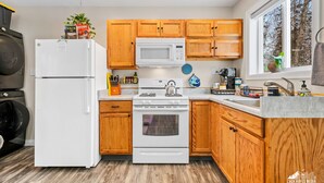 A modern kitchen with wooden cabinets, a white refrigerator, a stove, and a microwave. - Quiet and Cozy getaway cabin in Hatcher Pass, Alaska; 15 min. from Palmer! (Palmer)