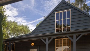 A dark wooden house with a front porch, a door, and windows. - 20 People / 9 Bedroom / 13 Beds Cabin Compound in the heart of Huskisson (Huskisson)