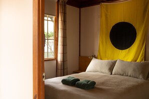 A room with a bed, a yellow curtain with a black circle, and a window with bamboo blinds. - Seahorse Manor  - Huskisson (Huskisson)