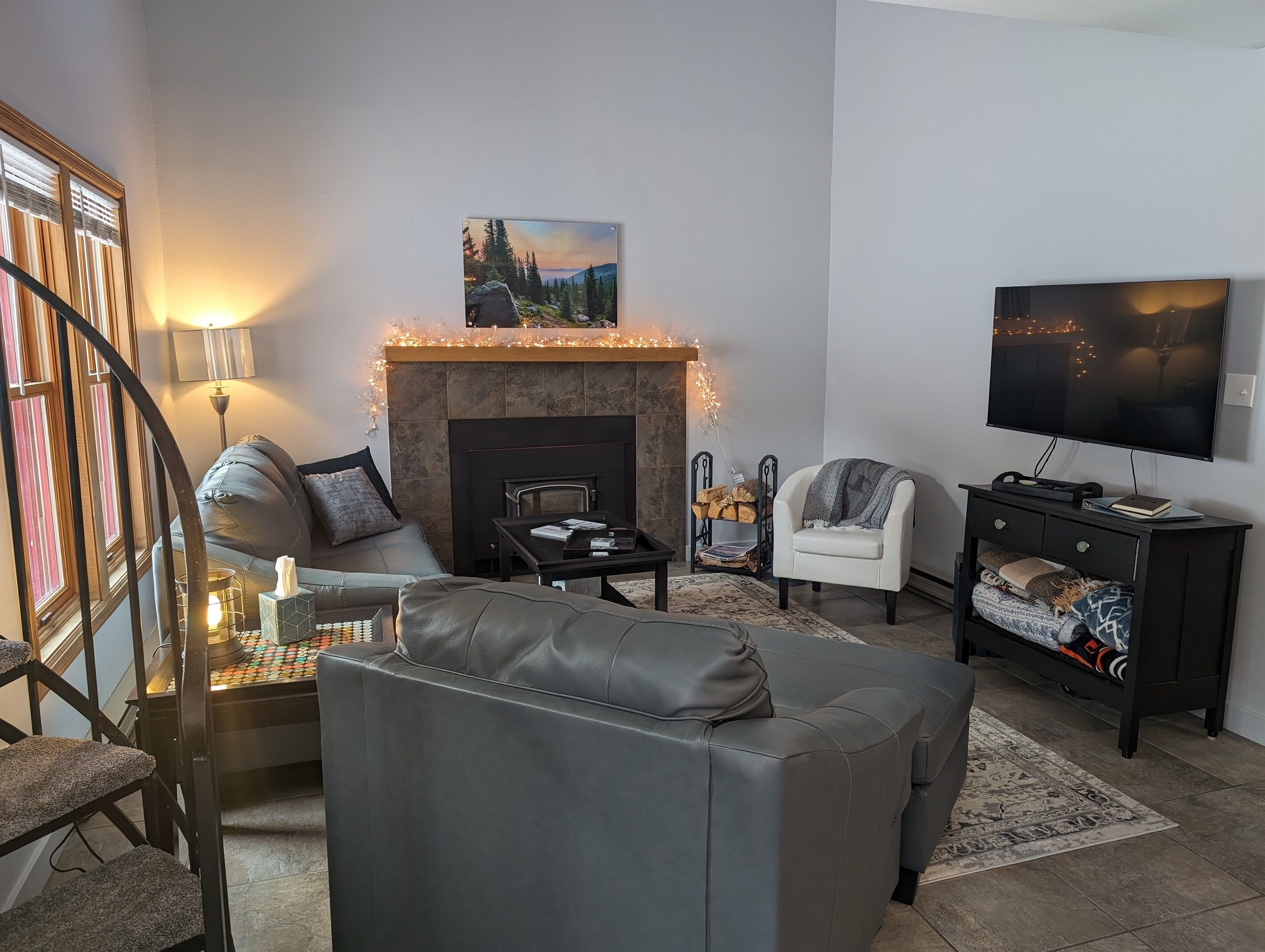 Ein Wohnzimmer mit Kamin, Sofa, Sessel und Fernseher.