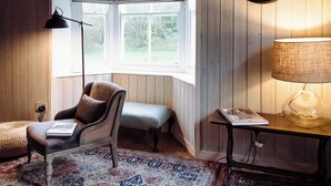 A corner room with a window, a lamp, a chair, a table, and a mirror. - 1 bedroom accommodation in Carlisle (Carlisle)
