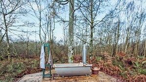 A wooden deck with a portable sauna, a green chair, and a whiteboard in a forested area. - 1 bedroom accommodation in Carlisle (Carlisle)