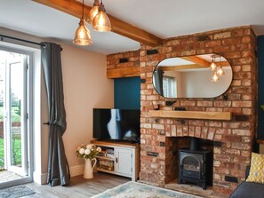 A living room with a brick fireplace, a television, and a wooden shelf.