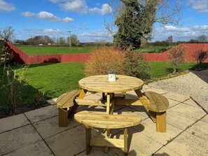 A wooden picnic table with benches in a garden setting.