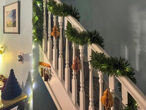 A staircase with white balusters, decorated with green garlands and golden ornaments.