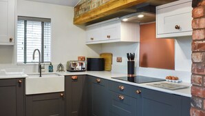 Eine moderne Küche mit Ziegelwand, einem Fenster mit Jalousien, einer Spüle, einem Toaster und einem Messerblock.