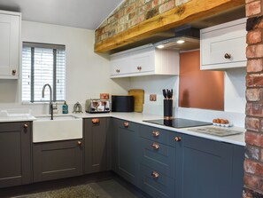 A modern kitchen with a brick accent wall, a window with blinds, a sink, a toaster, and a knife block. - 3 bedroom accommodation in Slingsby, near Malton (Slingsby, near Malton)