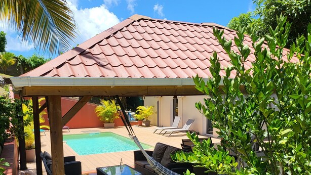 A covered outdoor seating area with a pool, lounge chairs, and a hammock. - Grande Anse Haut de Villa 6 Pers, Piscine Privée, mer et Commerces 6mn à Pieds (Les Trois-Îlets)
