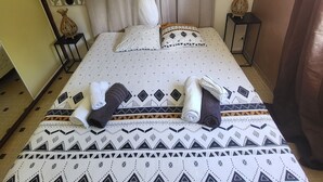 A neatly made bed with a patterned bedspread, a white canopy, and a decorative wall piece. - Grande Anse Haut de Villa 6 Pers, Piscine Privée, mer et Commerces 6mn à Pieds (Les Trois-Îlets)