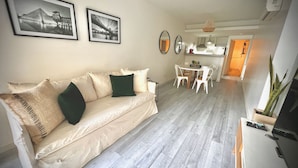 A living room with a beige sofa, two framed photographs on the wall, a dining area with a white table and chairs, and a kitchen area visible in the background. - Apartments Bariloche - Palermo Viejo, Cerviño (Buenos Aires)