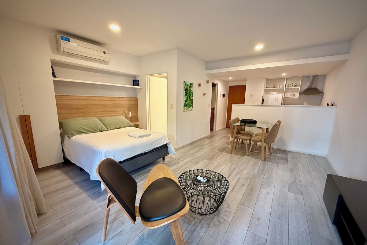 Ein kleines Hotelzimmer mit einem Bett, einem Esstisch und einem Stuhl.