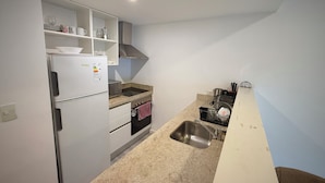 A compact kitchen with a built-in refrigerator, microwave, oven, and sink. - Apartments Bariloche - Palermo Viejo, Cerviño (Buenos Aires)