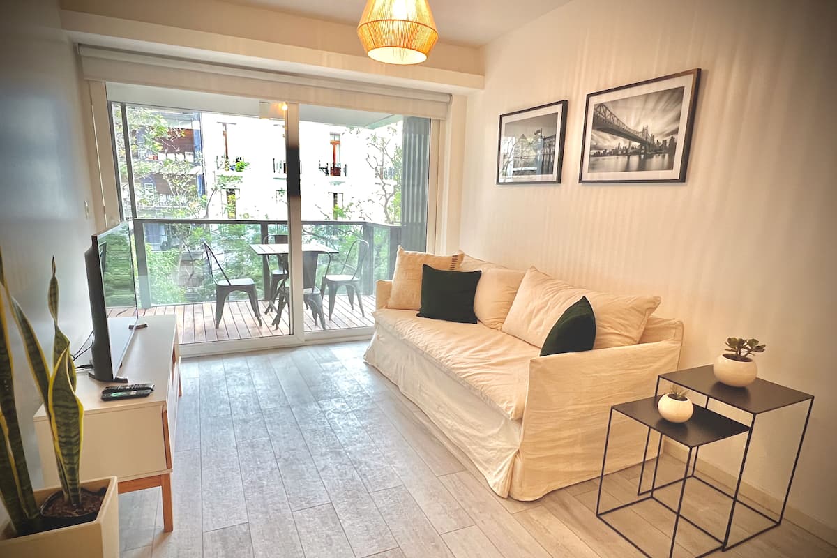Ein gemütliches Wohnzimmer mit einer Couch, einem kleinen Tisch und einer Topfpflanze.