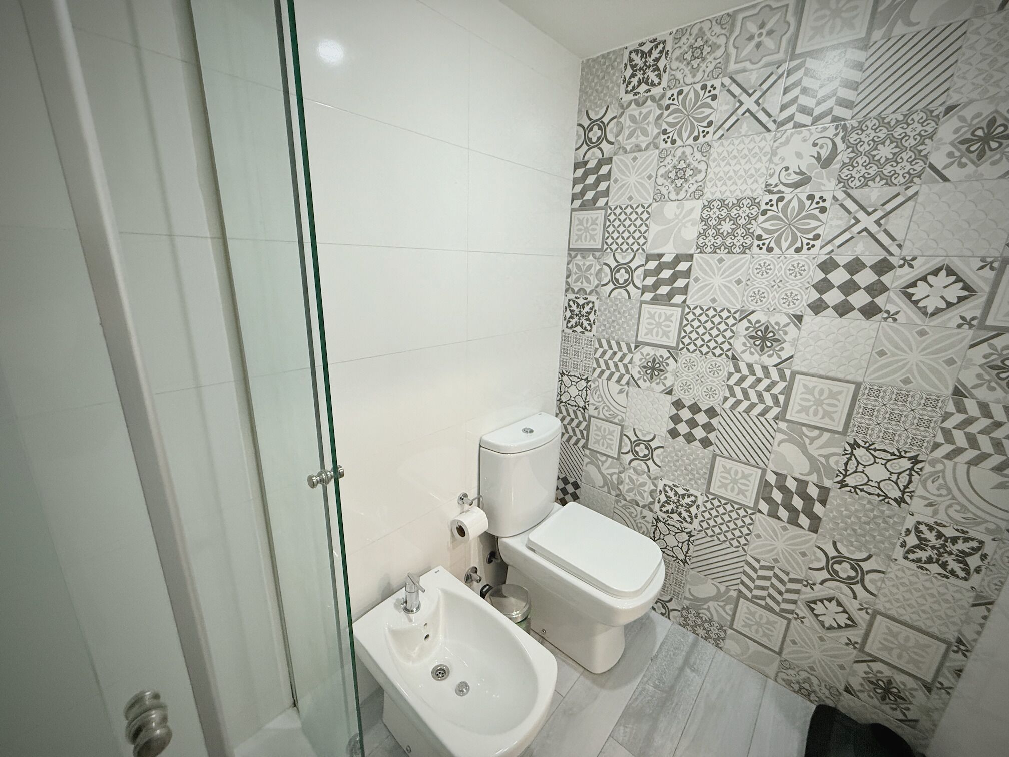 Une salle de bain équipée de toilettes, d’un bidet et d’une douche à parois de verre.