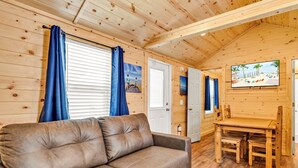 A cozy cabin interior with a leather sofa, wooden dining table, and chairs. - Good Times Motel and Marina  (Steinhatchee)