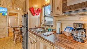 A wooden cabin interior with a kitchen area, including a refrigerator, sink, and coffee maker. - Good Times Motel and Marina  (Steinhatchee)