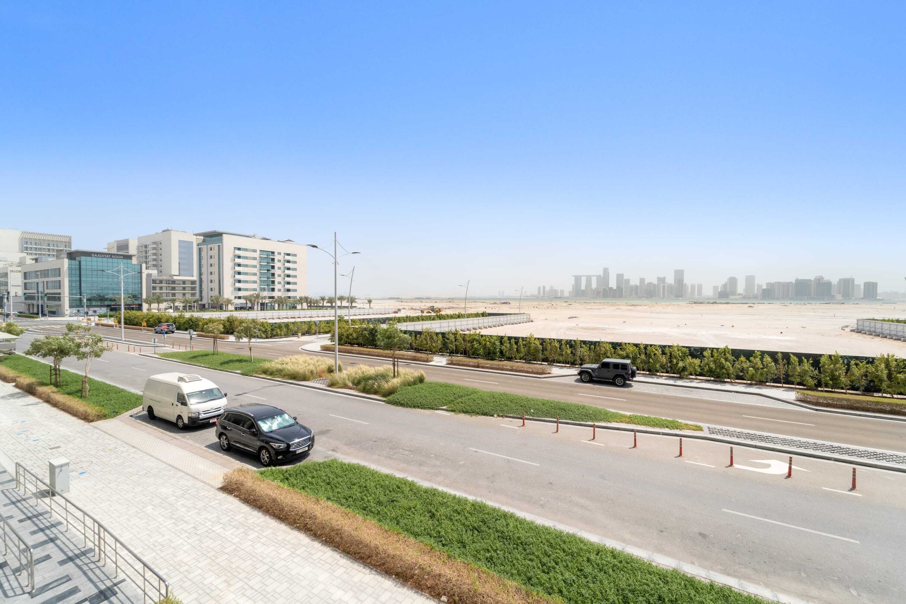 A modern urban road with a white van and a black car parked on the side.