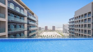 A modern hotel with a pool overlooking a beach and cityscape. - Silkhaus Park View Tower - Saadiyat Island (Abu Dhabi)
