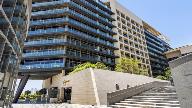 A modern building with multiple floors, a prominent entrance, and a staircase leading to the entrance. - Silkhaus Park View Tower - Saadiyat Island (Abu Dhabi)