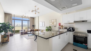 A modern kitchen with a central island, white cabinetry, and a built-in oven. - Silkhaus Park View Tower - Saadiyat Island (Abu Dhabi)