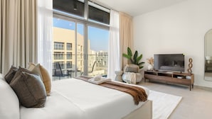 A modern hotel room with a large bed, a TV, and a balcony with a view of the city. - Silkhaus Park View Tower - Saadiyat Island (Abu Dhabi)