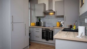 A modern kitchen with grey cabinets, a microwave, a stove, and a sink.