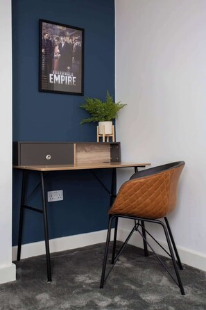 A desk with a plant, a framed picture, and a chair in a room with blue walls and carpet. - Vacant Nests - Atlantic City - Prime Location (Tyne and Wear)
