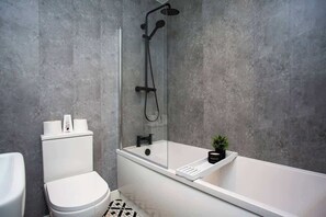 Et moderne badeværelse med toilet, badekar og brusekabine.