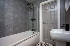 A bathroom with a bathtub, shower, and sink. - Bondi beach Getaway - One bedroom apartment (Tyne and Wear)