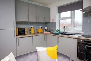A modern kitchen with grey cabinets, a microwave, a coffee machine, and a dishwasher. - Bondi beach Getaway - One bedroom apartment (Tyne and Wear)